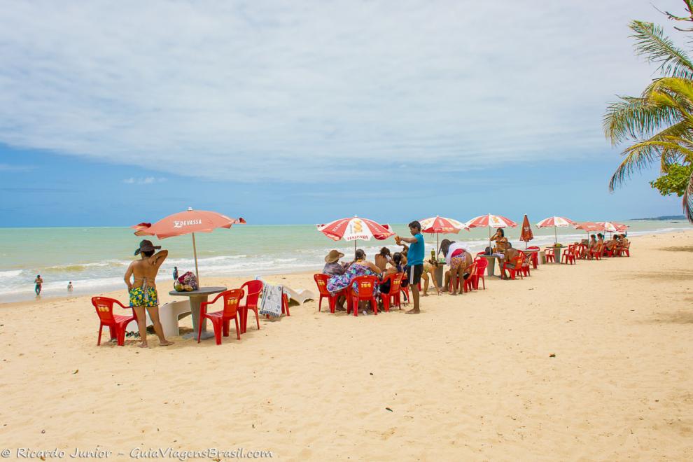 Imagem de um menino servindo turistas nas areias da praia.